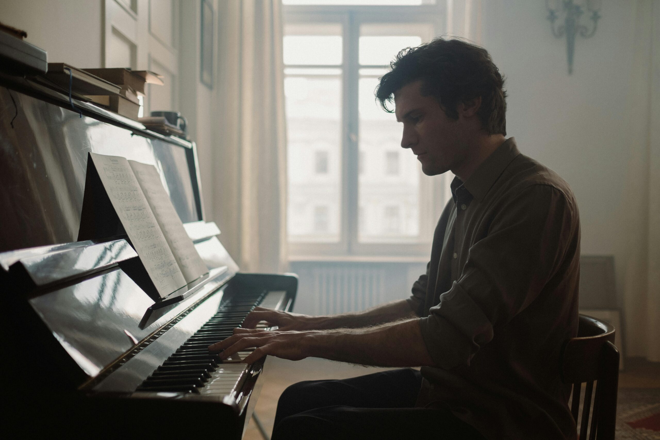 A man playing piano in a softly lit room, creating a peaceful atmosphere.