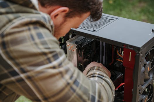 A man cleans and maintains a desktop PC outdoors with precision.